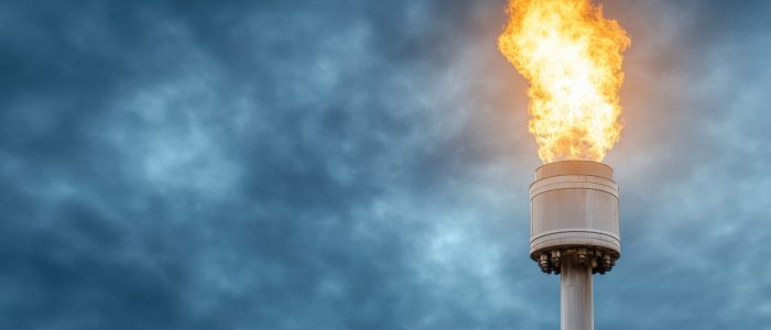 A Flare tower at oil refinery burning excess gases against dramatic sky